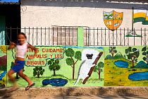 Young girl runs past mural which promotes protection of the Cotton-top tamarin. Los Limites, Colombia, South America. February 2008