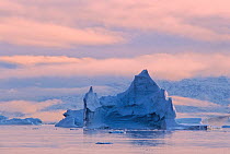 Sunset in a small fjord within Scoresby Sund, dotted with icebergs and bordered by fog-shrouded mountains covered with snow. Hurry Inlet, Scoresby Sund, East Greenland.