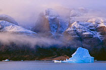 View of iceburg within narrow fjord, which is almost 50 nautical miles long, 4 to 5 nautical miles wide, and 1000 metres deep, flanked by mountains Ofjord, within Scoresby Sund, Greenland