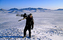Cameraman Tom Clarke carrying filming equipment in the Gobi Desert during production of 'Deserts' episode of BBC Series Planet Earth, Mongolia, January 2004.
