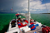 Boys in the cockpit of 30ft Tiki catamaran "Abaco" anchored in the Exumas, Bahamas, Caribbean. June 2009. Model and property released.