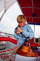 Boy winching aboard 30ft Tiki catamaran "Abaco". Exumas, Bahamas, Caribbean. June 2009, Model and property released.