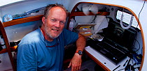 Photographer, Onne van der Wal, below decks working on laptop. Aboard 30ft Tiki catamaran "Abaco". Exumas, Bahamas, Caribbean. June 2009, Model and property released.