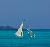 Two boats sailing on turquoise seas during the Bahamian Sloop regatta, Georgetown, Exumas, Bahamas. April 2009.