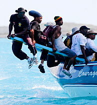 Crew riding the pry (hiking board/plank) during the Bahamian Sloop regatta, Georgetown, Exumas, Bahamas. April 2009.