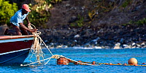 Man leaning over bow of boat, with fishing nets. Grenadines, Caribbean, February 2010.