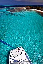 Couple sunbathing on the trampoline of a catamaran in the Grenadines, viewed from the masthead. Caribbean. February 2010.