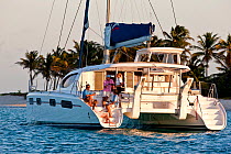 Friends relaxing on the aftdeck of a catamaran anchored in the Grenadines, Caribbean. February 2010. Model released.