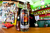 Man in bar holding a bottle of "Sunset Very Strong Rum", Grenadines, Caribbean. February 2010. Editorial use only.