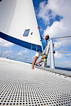 Man standing beside sail, cruising in the Grenadines, Caribbean. February 2010. Model released.
