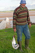 Traditional salmon fisherman (putchers in background) with Atlantic salmon (Salmo salar)catch. This traditional Severn Estuary way of life is threatened by the proposed barrage. July 2009