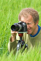Portrait of camerman Tim Shepherd, taking stills  for the BBC in a Wheat field, UK, June 2007