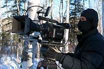 Cameraman Keith Brust filming with Red Camera, in Birch woodland (Betula papyrifera) for BBC Life series, Minnesota, USA, March 2008