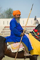 Domestic horse, a traditionally dressed Nihang (an armed Sikh soldier) mounted on his horse holding a spear during the Maghi Mela festival, Mukstar, Punjab, India. Janaury 2010