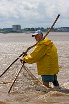 Lave fisherman, fishing for Salmon using traditional methods, with decommissioned Berkeley nuclear power station behind. This way of life is potentially under threat from proposed barrage. Gloucesters...