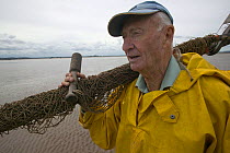 Portrait of Lave fisherman, carrying net which he uses to fish Atlantic Salmon, on the Severn estuary. This traditional way of life is potentially under threat from proposed barrage. Gloucestershire,...
