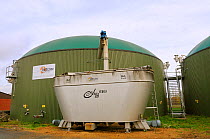 Biogas plant with fermenting chamber for methane production from maize silage, with silage hopper in foreground. Cornau, near Vechta, Lower Saxony, Germany.