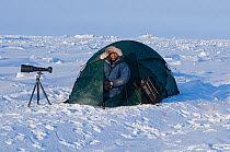 Photographer Steven Kazlowski with camera, tripod and tent, camping on location within the Arctic National Wildlife Refuge, Alaska April 2009