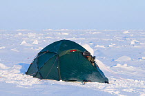 Photographer Steven Kazlowski with camera, tripod and tent, camping within the Arctic National Wildlife Refuge, Alaska. April 2009