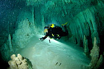 Diver exploring a freshwater Limestone sinkhole / Cenote called 'The Pit' - a traverse to 'The Blue Abyss' with stalactites and stalagmites, Tulum, Quintana Roo, Mexico, September 2008. Model released