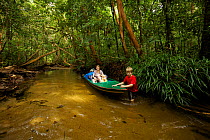 Mother and two young children (all model released)traveling by boat downstream from the research camp in Gunung Palung NP Borneo. July 2007