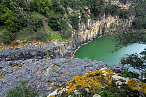 View of the Fiora river, which has excavated the tufaceous layer, exposing the lava flow made of black Tephrite rocks and forming Pellicone lake, Vulci archaeological and nature park, Lazio, Italy. Ma...
