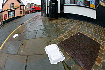 Litter in the form of a plastic carton scattered over the streets of a small town. Wales, UK July 2008