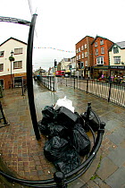 Uncollected council waste bags from businesses, in the streets of a small town. Wales, UK July 2008