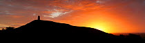 Panoramic view of Glastonbury Tor at dawn with  glowing sky just before sun rises.  Somerset, England, UK, 2009. Digital Composite.