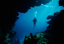 Scuba diver exploring underwater cave entrance, Sinai, Egypt, Red Sea Model released Model released.