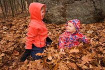 Brother and sister playing in woodland amongst fallen leaves, Lexington, Massachusetts, USA, December 2004, Model released