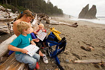 A mother and her children looking at educational material on the beach in Olympic National Park, Washington, USA, August 2005, Model released