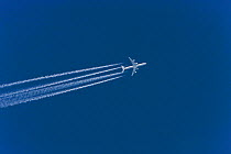 Airplane flying with vapour trails against blue sky, Germany, April 2010.