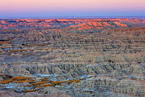 View of Badlands National Park with far peaks illuminated by rising sun, South Dakota, USA. September 2009.