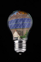 Photovoltaic solar panels on roof of house inside incandescent lamp / bulb against black background Digital composite