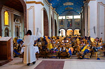 A group of costumed dancers from the Oruro Carnival, sitting and bowing to the virgin in a Cathedral, Bolivia, February 2009.