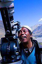 Portrait of a Nepalese sherpa looking through viewfinder of film camera, on location in the Kali Gandaki Valley, Nepal, for BBC Planet Earth series, 2005