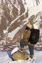Porter carrying film crew equipment, above Chitral town in the Hindu Kush mountains, North West Frontier, Pakistan, during filming for BBC Planet Earth series, Mountains episode, 2005.
