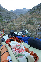 Member of film crew sleeping on mountain side while tracking snow leopard (Panthera uncia) Chitral, Hindu Kush, NW frontier, Pakistan. filming for BBC Planet Earth series 2005