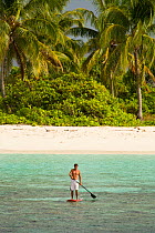 Man paddle boarding around small uninhabited island, Ari Atoll, Maldives. November 2008. Model released