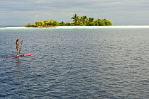 Woman paddle boarding around small uninhabited island, Ari Atoll, Maldives. November 2008. Model released