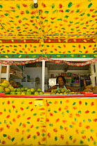 Portrait of local vendor selling tropical fruit at colourful roadside market stop outside of Argyle Falls Forest, Tobago, Caribbean. March 2008.
