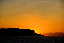 Sunset on Baffin Island, with mountain silhouetted against sky, Nunavut, Canada, August 2010