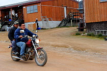 Two Inuit men driving through Qikiqtarjuaq village on a motorbike, Baffin Island, Nunavut, Canada, August 2010
