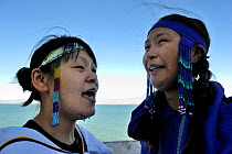 Two young Inuit women singing Inuit songs, wearing traditional beaded headbands, Pond Inlet village, Baffin Island, Nunavut, Canada, August 2010