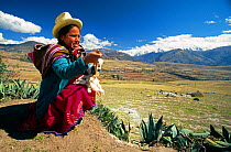 Quechua woman in traditional dress spinning wool, Andes mountains, Peru.