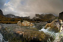 Mountain landscape, The Glyders, with view of flowing freshwater stream in foreground, showing water turbulence around rocks, Snowdonia NP, Gwynedd, Wales, UK. December 2009.