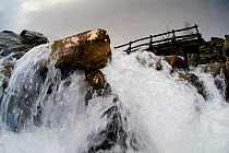 A view through a waterfall showing water turbulence around rocks, Snowdonia NP, Gwynedd, Wales, UK. December 2009.