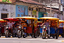 Mototaxis with passengers in busy urban streets, Iquitos. Loreto. Peru. October 2009