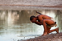 Kalahari bushmen, hunter drinking and refreshing at waterhole in central Kalahari desert, Botswana, November 2008